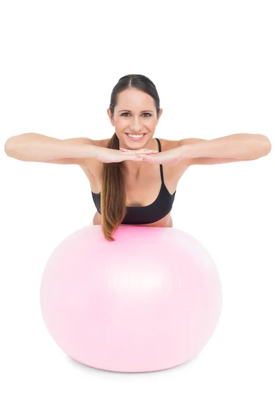 Retrato de una mujer sonriente en forma estirándose sobre una pelota de fitness — Foto de Stock