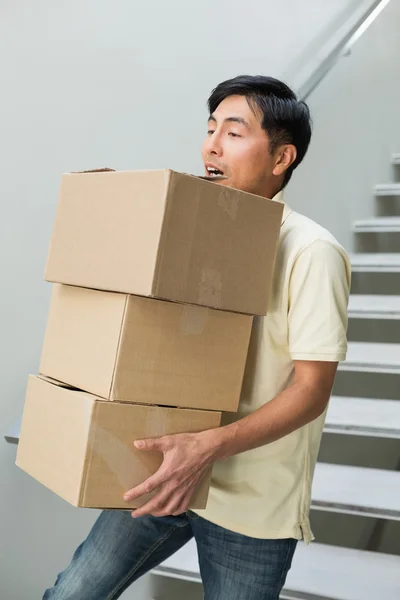 Giovane uomo che trasporta scatole contro scala — Foto Stock