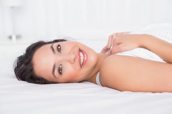 Lächelnde hübsche junge Frau entspannt sich im Bett — Stockfoto