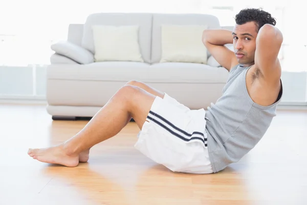 Giovane uomo che fa addominali crunches in soggiorno — Foto Stock