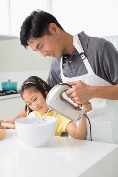 Man with daughter using electric whisk into bowl in kitchen — Stock Photo, Image