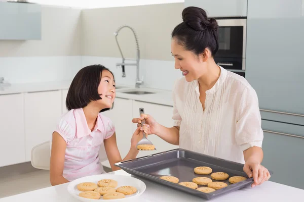 彼女の母親を見て女の子キッチンでクッキーを準備します。 — ストック写真