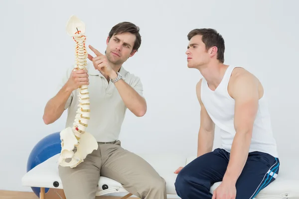 Fisioterapeuta amigable explicando la columna vertebral a un paciente — Foto de Stock