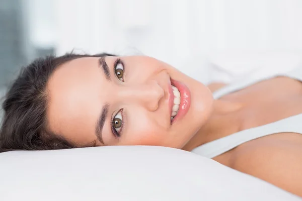 Primo piano di una bella donna sorridente sdraiata a letto — Foto Stock