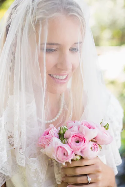 Lächelnde Braut mit Schleier über dem Gesicht und Blumenstrauß — Stockfoto