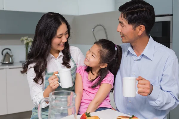 Happy young girl enjoying breakfast with parents — Stock Photo, Image