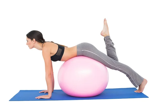 Vue latérale d'une femme en forme qui s'étire sur une balle de fitness — Photo