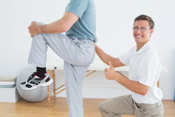 Therapist massaging mans lower back while gesturing thumbs up — Stock Photo, Image