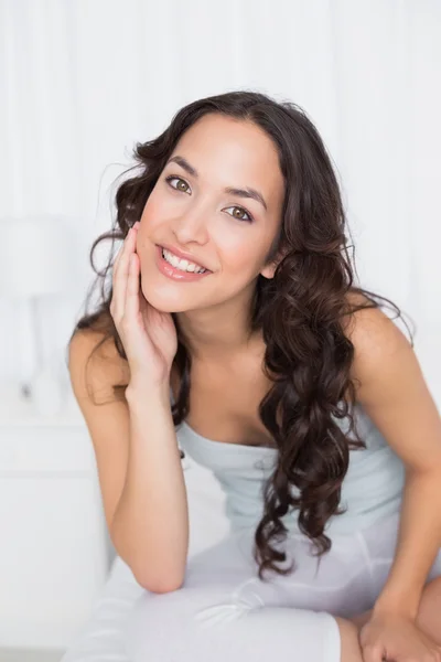 Sonriente guapa morena sentada en la cama en casa —  Fotos de Stock