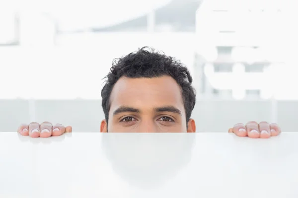 Empresario espiando detrás del escritorio en la oficina — Foto de Stock