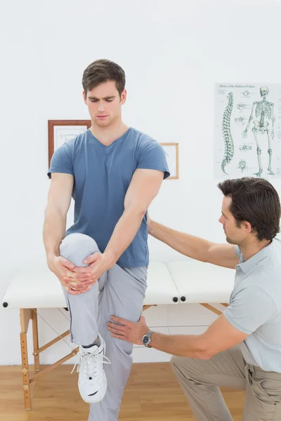 Terapeuta masculino assistindo homem com exercícios de alongamento — Fotografia de Stock