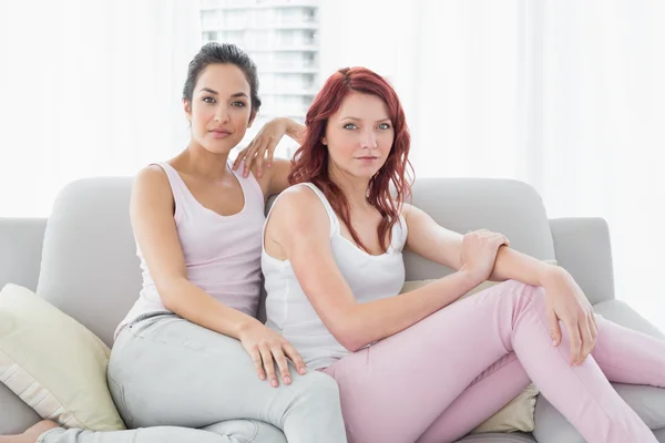 Two serious beautiful female friends sitting in the living room — Stock Photo, Image