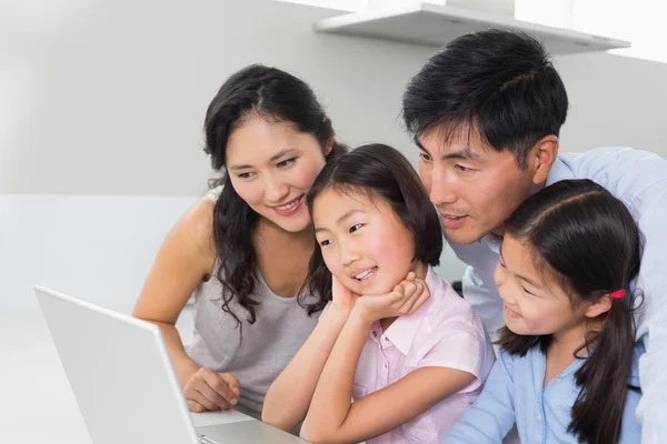 Family of four using laptop in kitchen