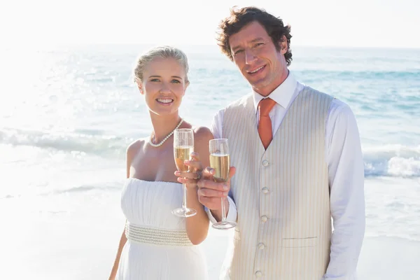 Recém-casados brindam com champanhe sorrindo para a câmera — Fotografia de Stock