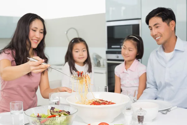 Glad kvinna som serverar spaghetti för familjen i köket — Stockfoto