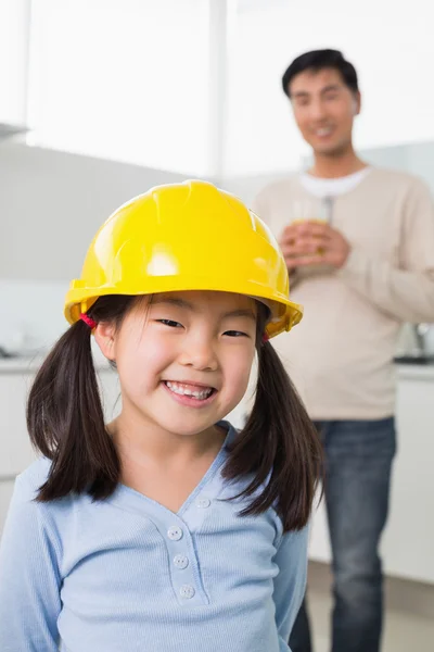 Roztomilá dívka v žluté čepice s otcem v pozadí — Stock fotografie