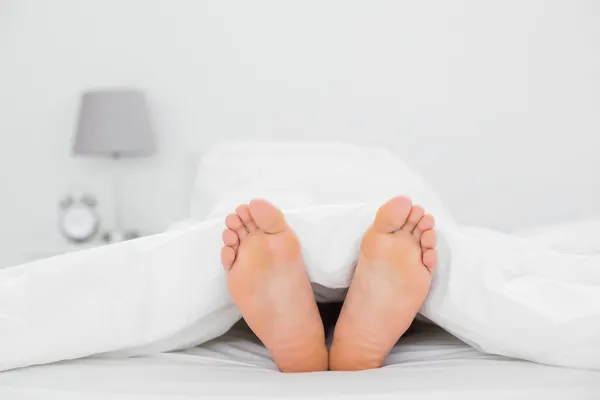 Close-up of bare feet in bed — Stock Photo, Image