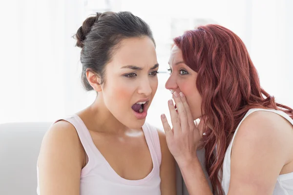 Jonge vrouwelijke vrienden thuis roddelen — Stockfoto