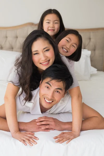 Alegre familia de cuatro acostados uno sobre el otro en la cama —  Fotos de Stock