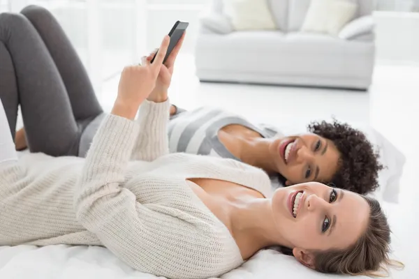 Entspannte Freundinnen lesen SMS im Bett — Stockfoto