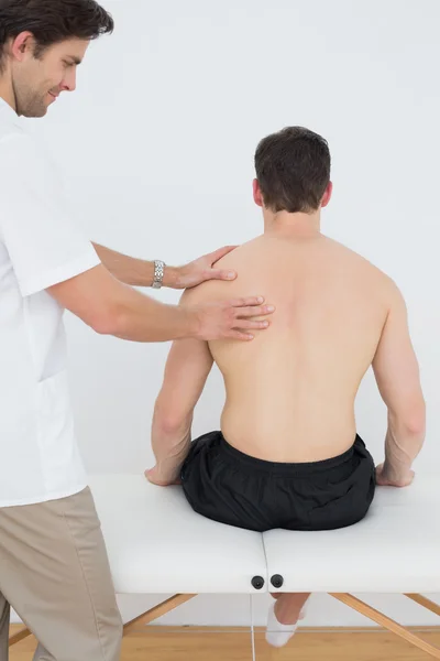Вид сзади на человека, которого массирует физиотерапевт — стоковое фото