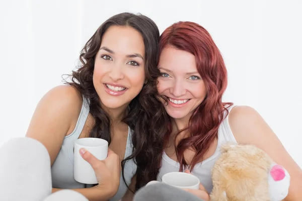 Porträtt av vänner med kaffekoppar i sängen — Stockfoto