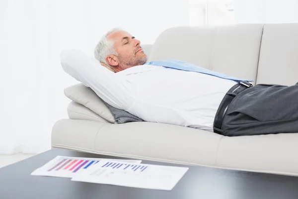 Zakenman slapen op de Bank met grafieken op tafel in woonkamer — Stockfoto