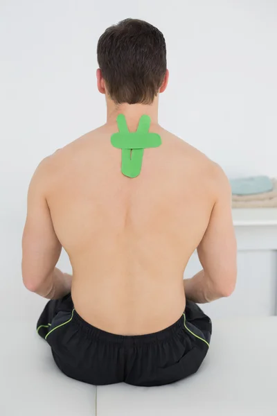 Visão traseira de um homem sem camisa com fita cinesio verde nas costas — Fotografia de Stock