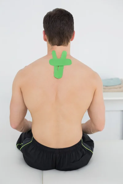 Bakifrån av en bar överkropp man med grön kinesio tape på baksidan — Stockfoto