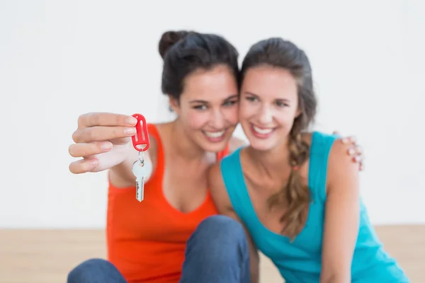 Vrienden met huis toetsen zittend op de vloer — Stockfoto