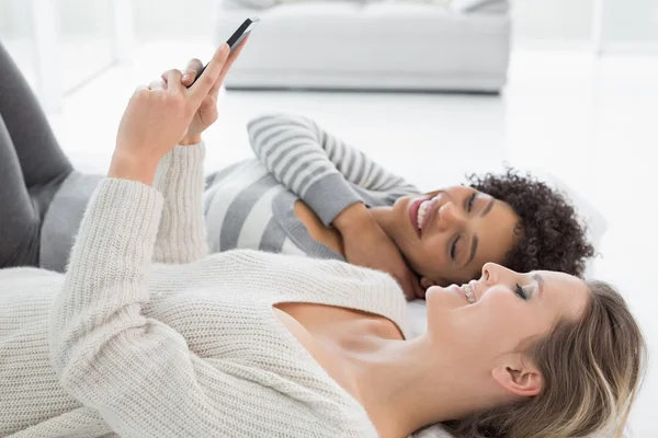 Relajadas amigas leyendo mensajes de texto en la cama — Foto de Stock