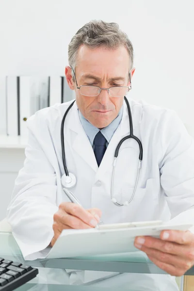 Doctor reading a report at medical office — Stock Photo, Image