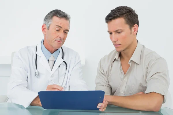 Arzt diskutiert Berichte mit Patient im Büro — Stockfoto