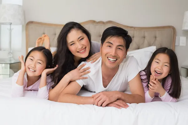 Cheerful family of four lying in bed — Stock Photo, Image