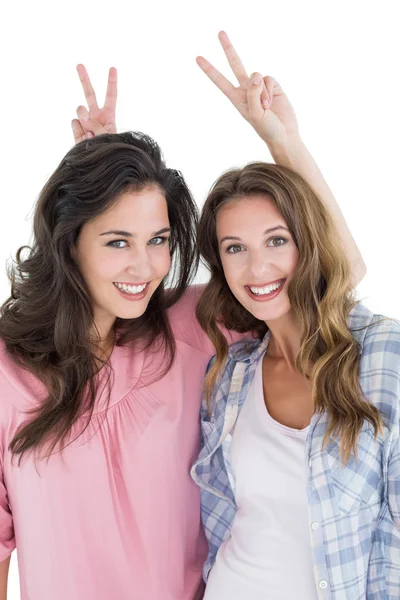 Female friends gesturing peace sign over heads — Stock Photo, Image