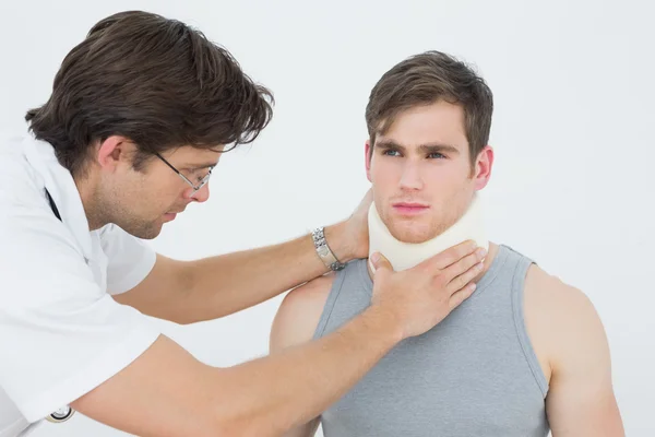 Mężczyzna lekarz badając pacjentów szyi — Zdjęcie stockowe