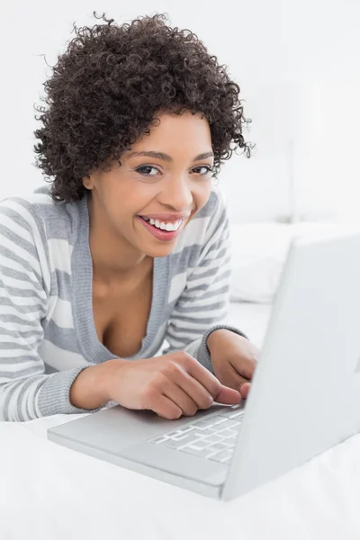 Μεγέθυνση του ένα χαμογελαστό γυναίκα χρησιμοποιώντας φορητό υπολογιστή στο κρεβάτι — Φωτογραφία Αρχείου