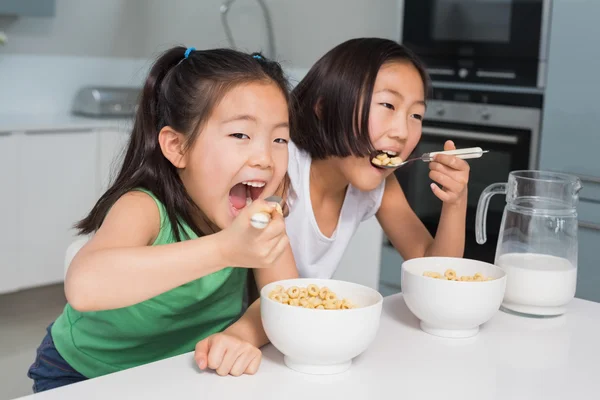 Twee jonge meisjes eten granen in keuken glimlachen — Stockfoto