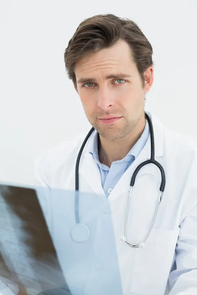 Концентрированный врач мужского пола смотрит на рентген позвоночника — стоковое фото