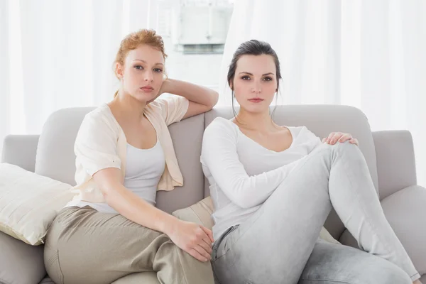 Two serious female friends sitting on sofa in the living room — Stock Photo, Image