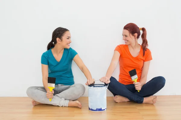 Amigos con pinceles y pintura pueden sentarse en una casa nueva — Foto de Stock