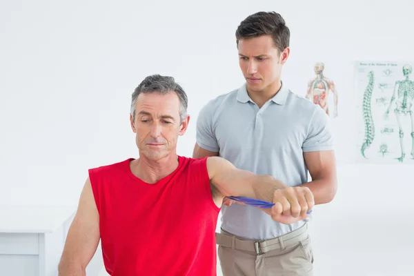 Fysiotherapeut onderzoeken een glimlachend volwassen mans arm — Stockfoto