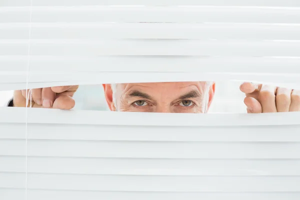 Retrato de perto de um homem de negócios espreitando pelas cortinas — Fotografia de Stock