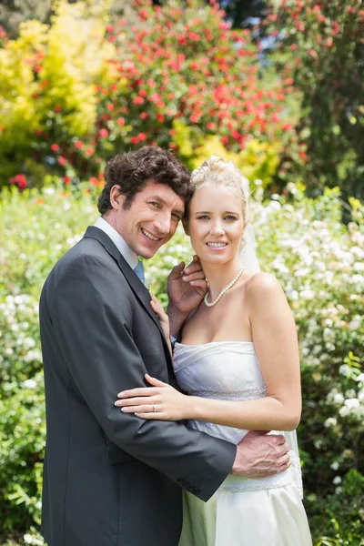 Romantic happy newlyweds embracing looking at camera — Stock Photo, Image