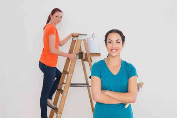 Vrouwelijke vrienden met verf penselen en ladder — Stockfoto