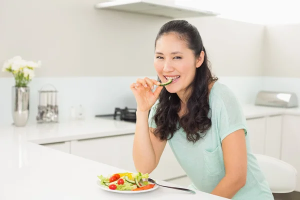 Portrait d'une jeune femme mangeant de la salade dans la cuisine — Photo