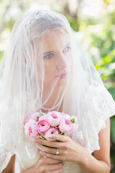 Content bride wearing veil over face holding rose bouquet — Stock Photo, Image
