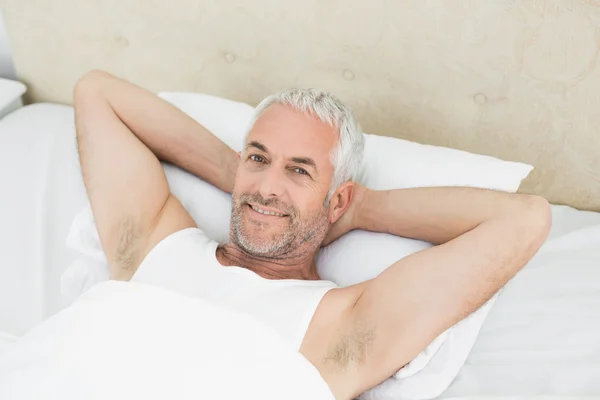 Portrét smějící se zralý muž odpočívá v posteli — Stock fotografie