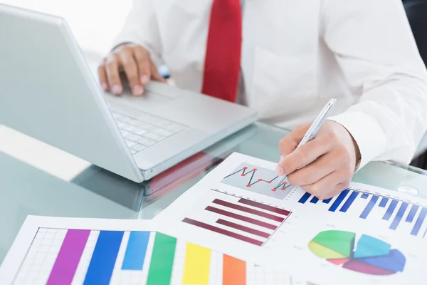 Mid section of a businessman with laptop and graphs — Stock Photo, Image