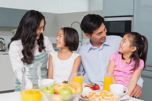 Família alegre de quatro desfrutando de café da manhã saudável na cozinha — Fotografia de Stock